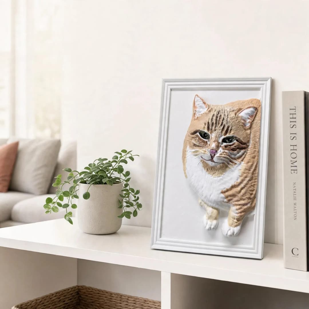 A finished hand-painted 3D cat relief in a white frame, displayed on a shelf at home