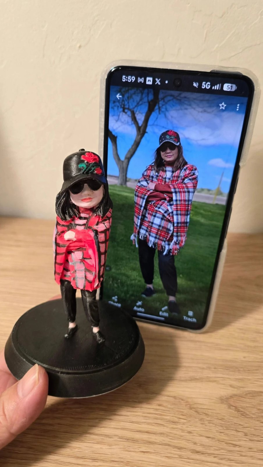 A finished hand-painted Mini Me figurine held beside the photo it was made from